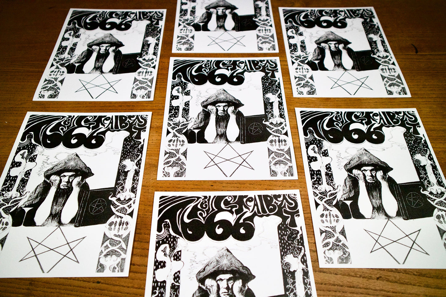 8 prints at an angle of A black and white pen and ink portrait of Aleister Crowley in a psychedelic art nouveau style, the text above reads The Great Beast 666